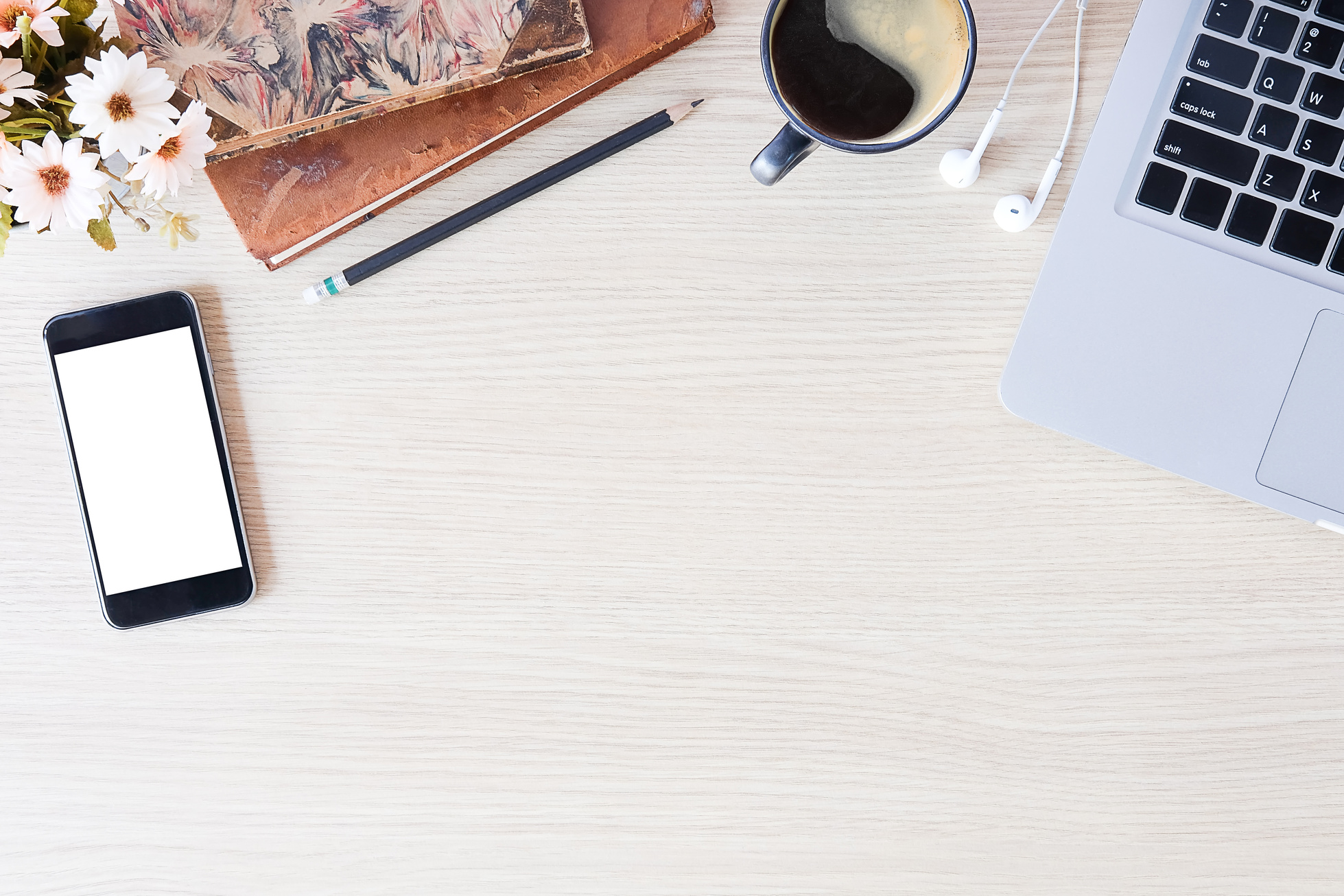 top view of a white wooden desk with a laptop, phone, coffee cup and flowers. Personal stylist Katie Jane preparing for a style discovery call.